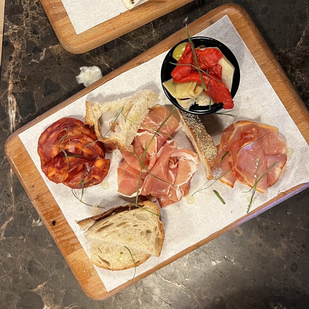 A charcuterie board with cured meats, sourdough, olives and roasted peppers at Tram Coffee & Wine